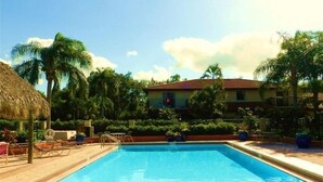 A swimming pool with lounge chairs, palm trees, and a building with a red roof. - Only 3-Miles to Gulf Beaches - Swim, Play Tennis or Just Relax (Bonita Springs)