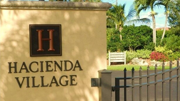 A gated entrance to Hacienda Village with a sign displaying the name and a large 'H' logo. - Only 3-Miles to Gulf Beaches - Swim, Play Tennis or Just Relax (Bonita Springs)