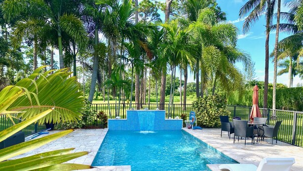 A rectangular swimming pool with a blue tiled edge, surrounded by a black metal fence. - Swans Nest West - Modern & Private, Heated Pool, 3 Brm (Lake worth)