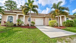 A two-story house with a front driveway, palm trees, and a clear blue sky. - Swans Nest West - Modern & Private, Heated Pool, 3 Brm (Lake worth)