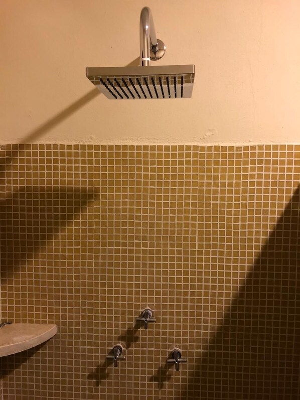 A shower area with a wall-mounted faucet and a tiled wall.