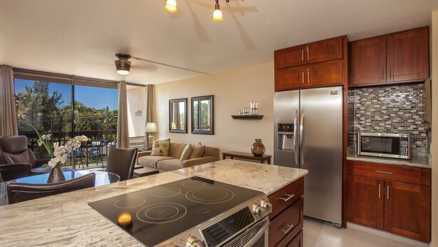 A modern kitchen with a large island, stainless steel appliances, and a view to the outside.