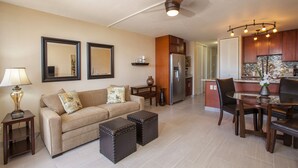 A modern living room with a sofa, ottomans, a coffee table, and a dining area with chairs and a table.