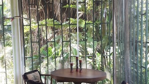 A conservatory with a round wooden table and four wooden chairs with cushioned seats.