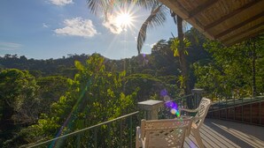 A balcony with a view of a lush forest and a clear sky.