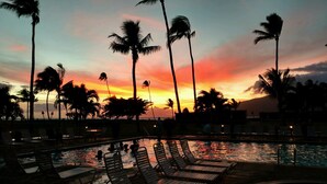 A poolside area with lounge chairs and palm trees against a sunset sky. - Maui Sunset B201: Beautiful 2 Bedroom, 2 Bath, Kihei Condo. Sleeps up to Six (Kihei)