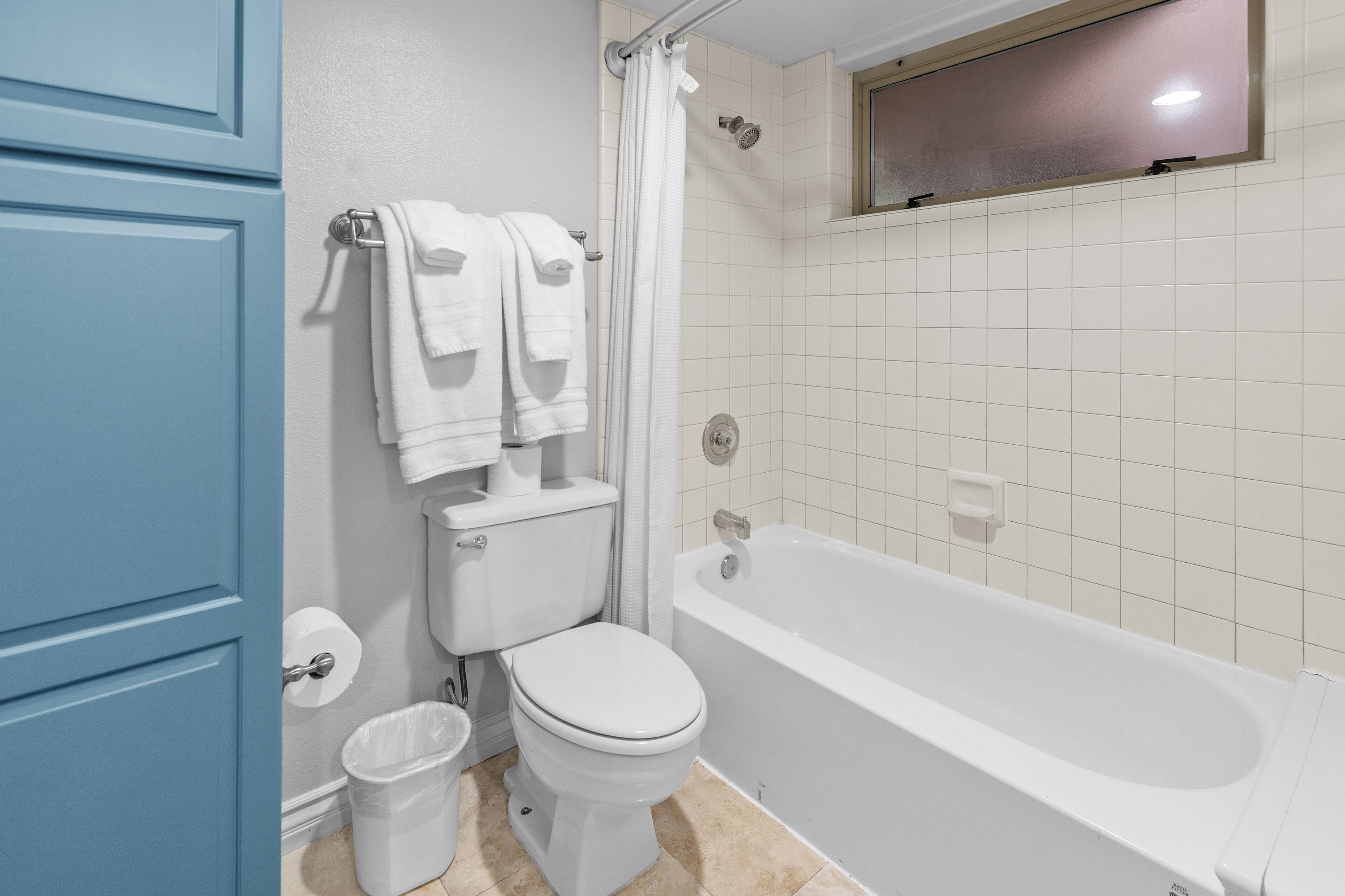 Un bagno con un WC, una vasca da bagno e una finestra sopra la vasca.