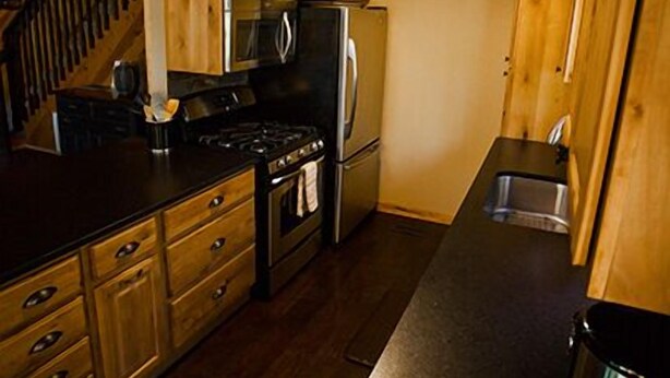 A compact kitchen with wooden cabinets, a stove, a refrigerator, and a sink.
