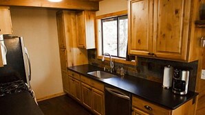 A kitchen with wooden cabinets, a black countertop, a stove, and a window.