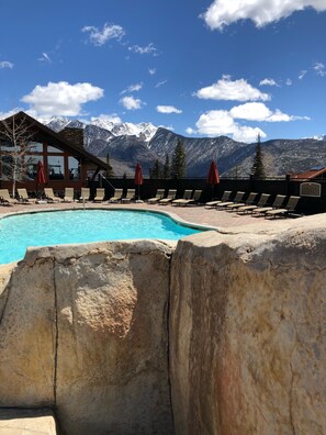 A pool area with lounge chairs and umbrellas, a wooden building, and a mountain backdrop. - Mountain Hideaway with Direct Access to Ski Slopes & Purgatory Mountain Resort  (Durango)