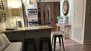 A kitchen with a central island, wooden flooring, and a dining area with a bench and stools. - Charming 2 bedroom condo in the heart of beautiful Natchez, MS. (Natchez)