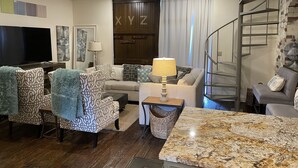 A living room with a TV, patterned chairs, a sofa, a lamp, and a marble countertop. - Charming 2 bedroom condo in the heart of beautiful Natchez, MS. (Natchez)