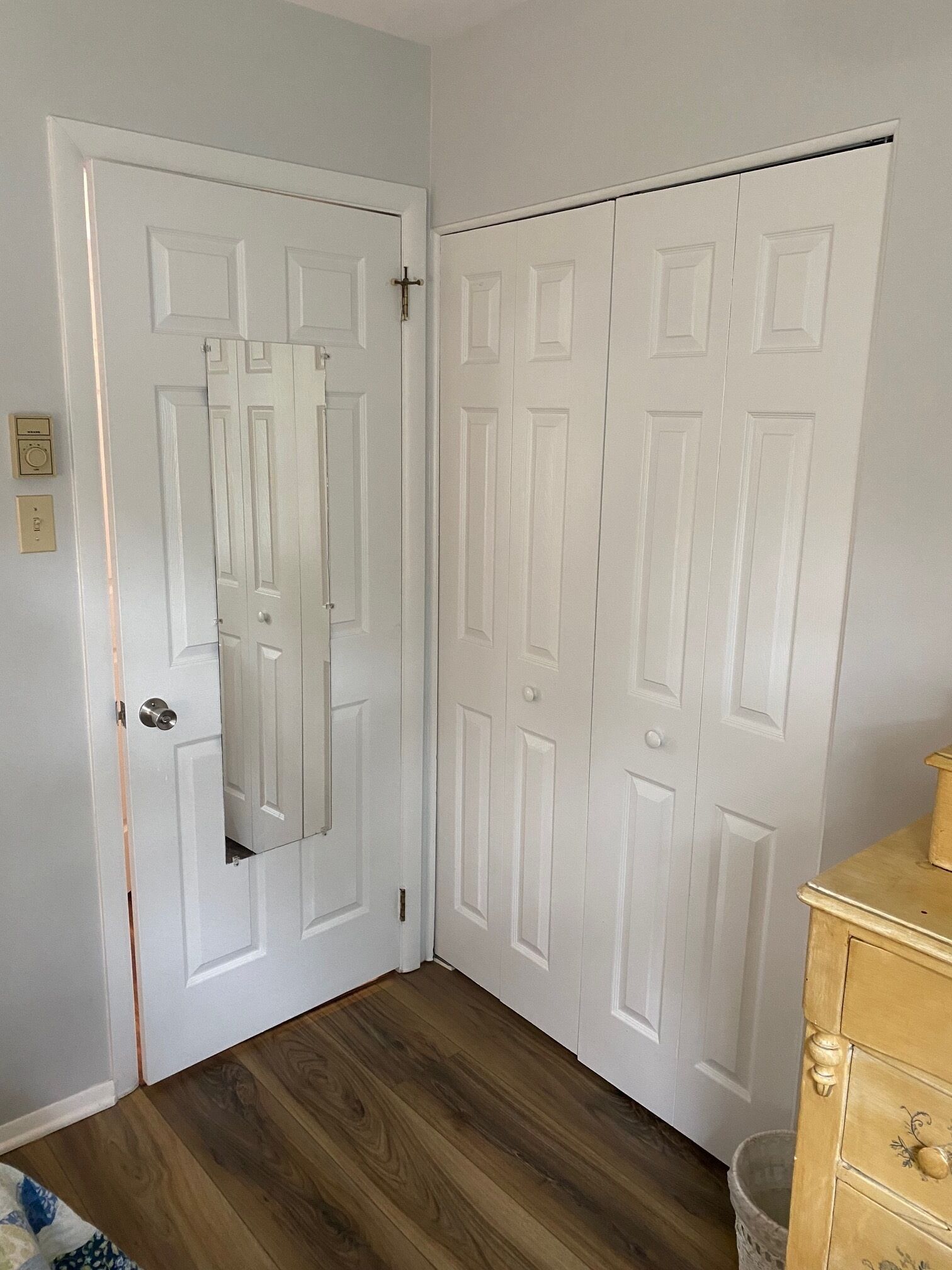 Une pièce avec une porte blanche, un plancher en bois et une commode en bois.