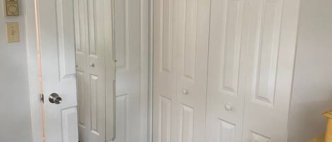 Une pièce avec une porte blanche, un plancher en bois et une commode en bois.