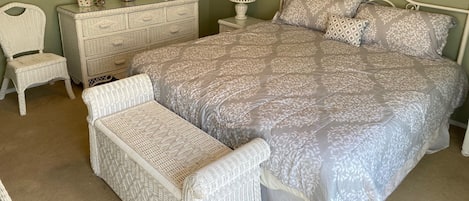Een slaapkamer met een groot bed, een dressoir, een stoel en een nachtkastje met een lamp.
