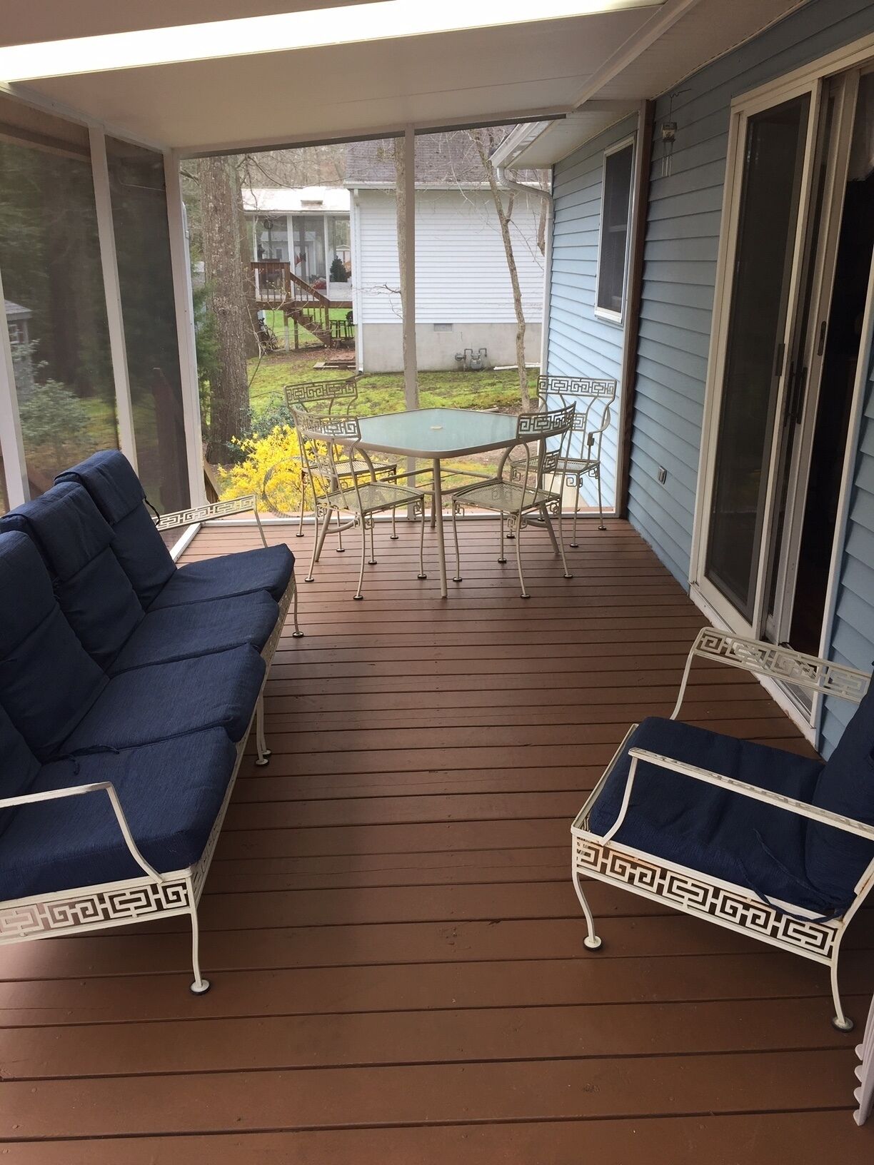 A covered patio with a table and chairs, a sofa, and a chair.
