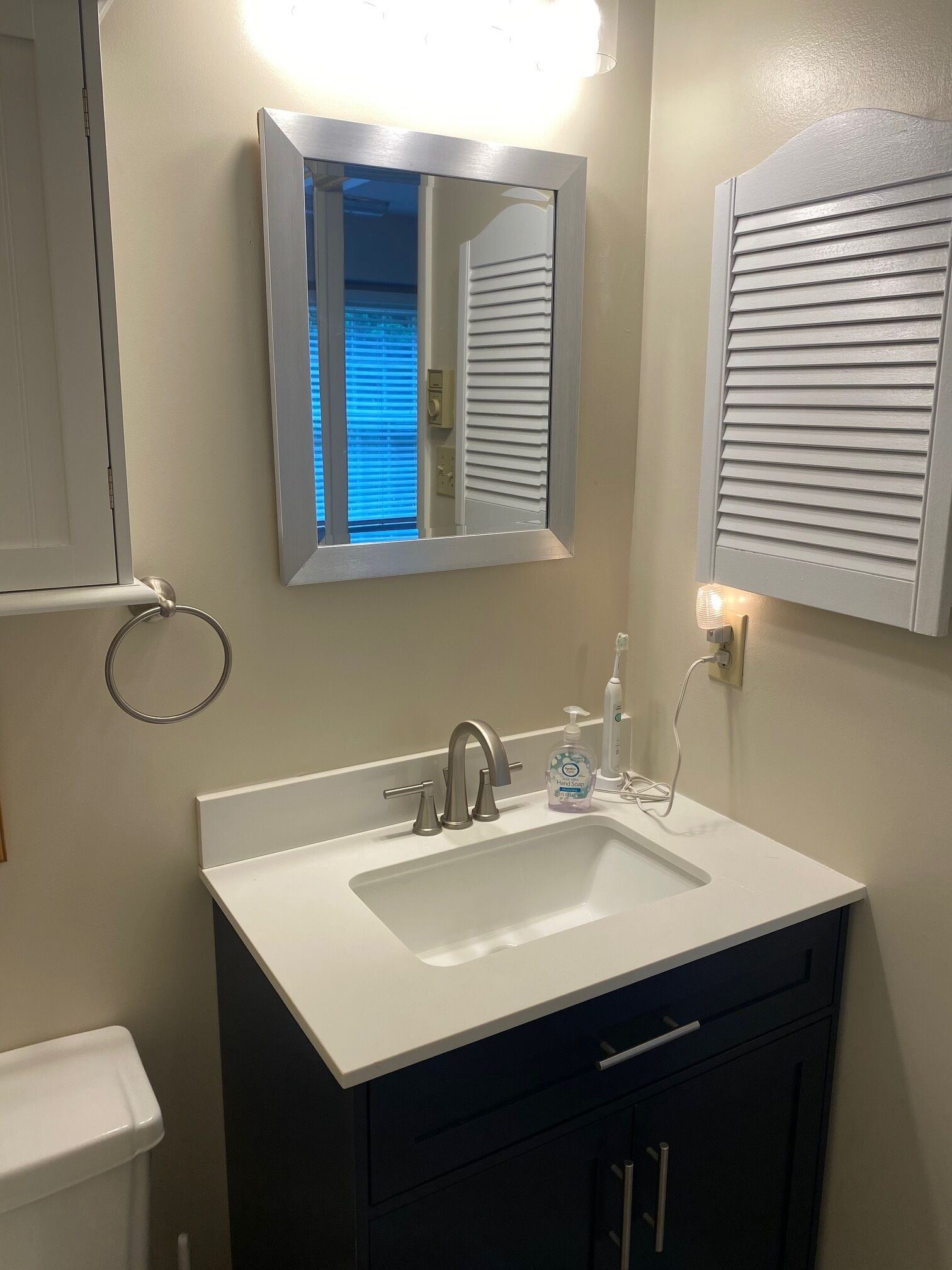 A bathroom with a white sink, a mirror, and a toilet.