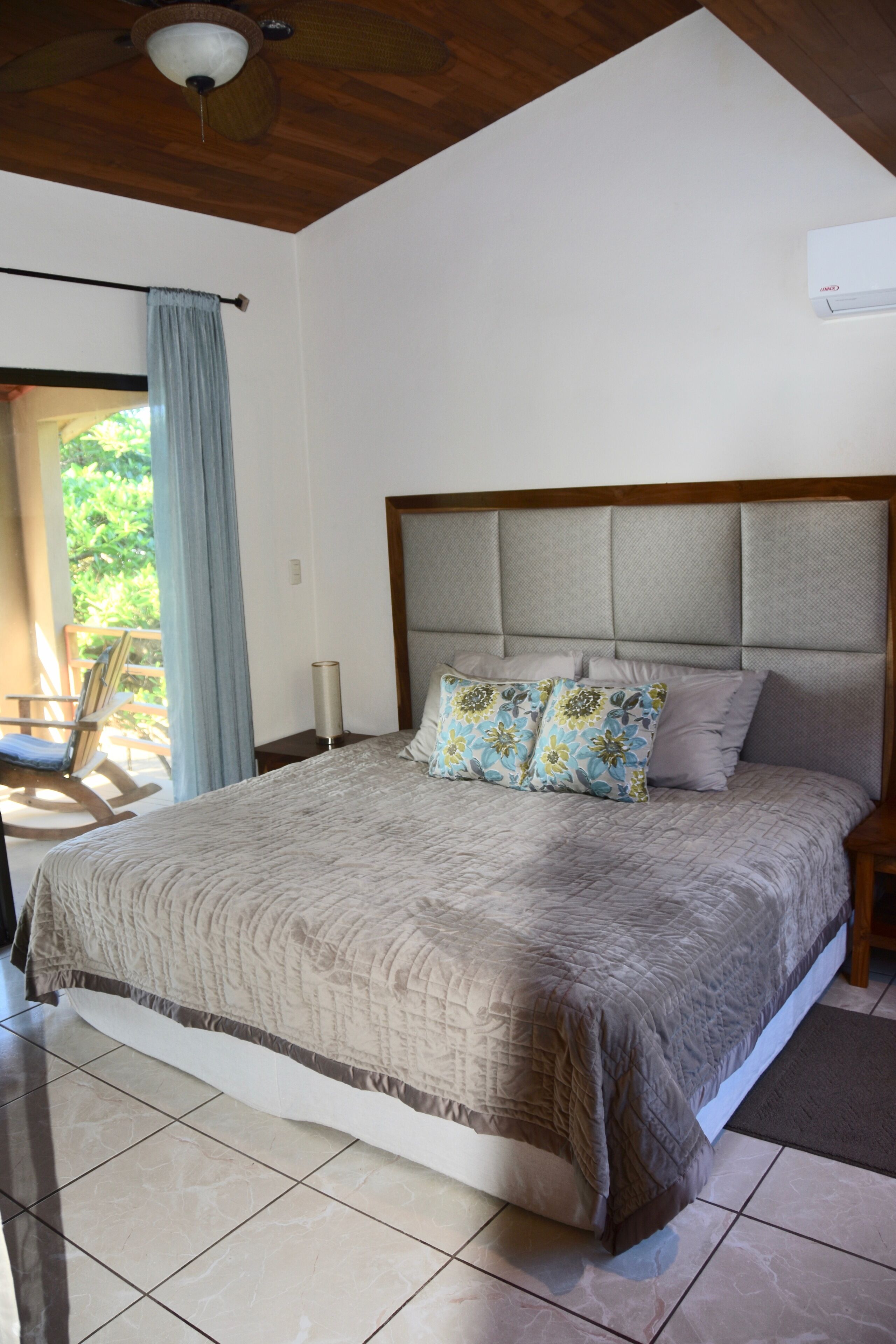 Una camera da letto con un letto grande, un soffitto in legno e vista sull'esterno.