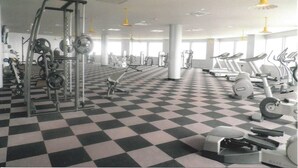 A gym with a checkered floor, various exercise equipment, and large windows.