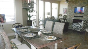 A dining area with a wooden table set for a meal, surrounded by wicker chairs.