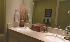 A bathroom with two sinks, a mirror, and a wooden chest of drawers.