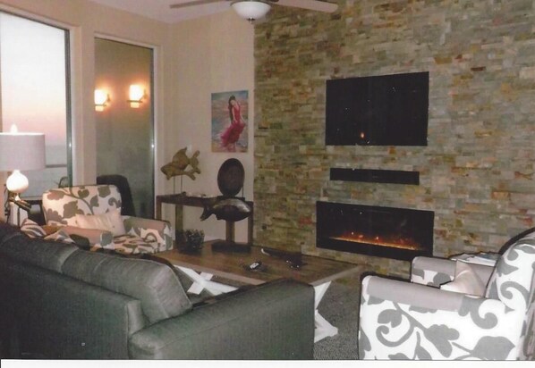 A living room with a stone wall, a fireplace, a television, and a sofa.
