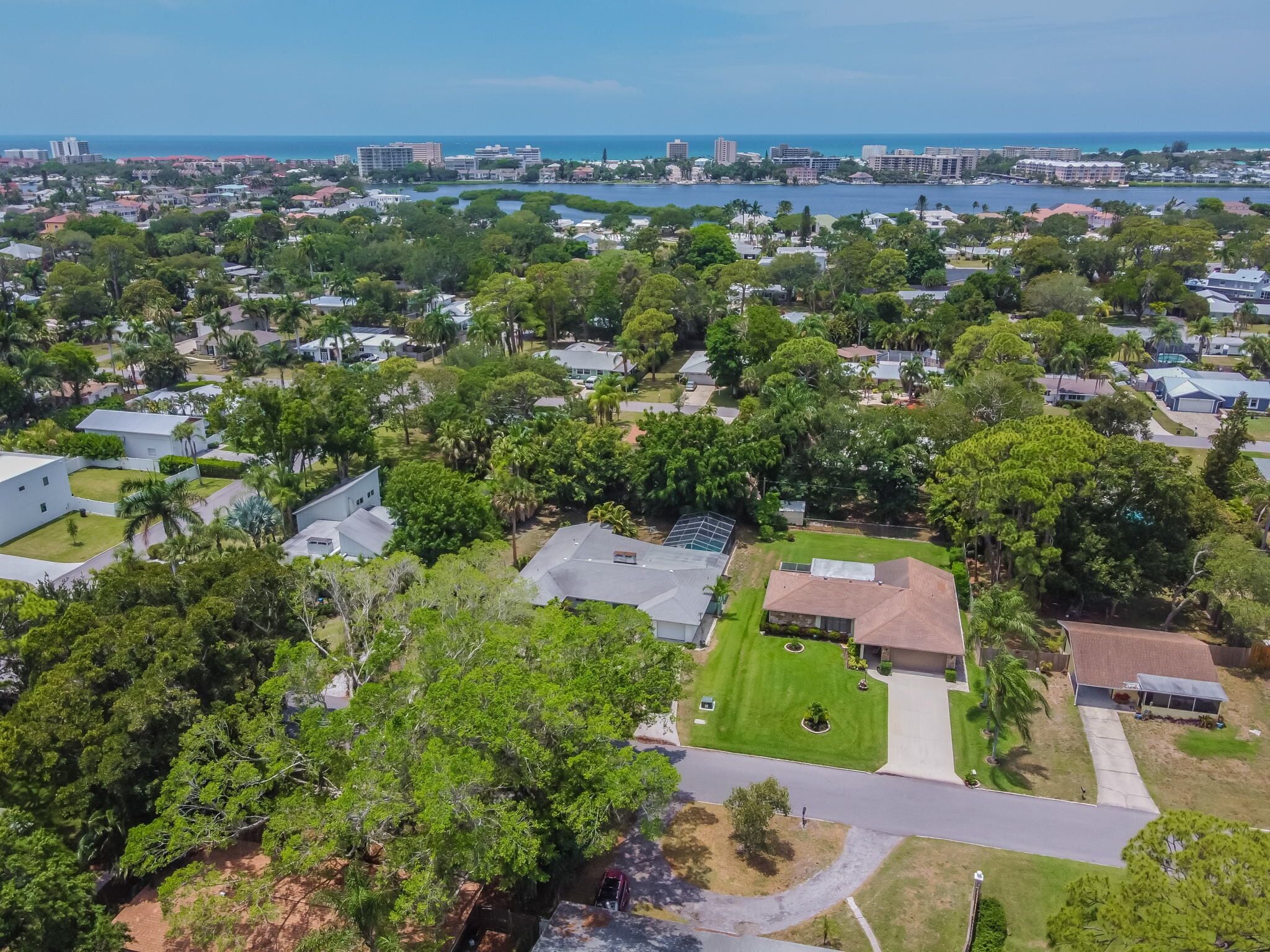 An aerial view of a residential area with houses, green spaces, and a waterfront.
