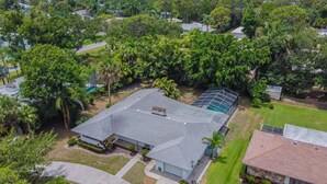 An aerial view of a residential area with a large house featuring a spacious backyard, a swimming pool, and a view of the ocean. - Siesta beach....one and only (Sarasota)