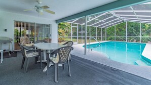 A covered outdoor area with a pool, a table with chairs, and a ceiling fan. - Siesta beach....one and only (Sarasota)