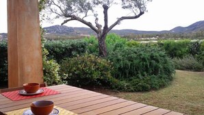 Ein Holztisch mit zwei Schalen und einer Tischmatte, draußen aufgestellt mit Blick auf einen Baum und Hügel im Hintergrund.