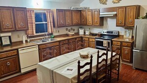 A kitchen with wooden cabinets, a stainless steel refrigerator, a stove, and a sink.