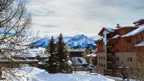 Un paese montano innevato, con edifici e una montagna imponente sullo sfondo.