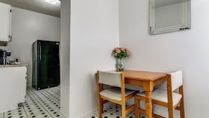 Ett kök med ett svart kylskåp, ett matbord med två stolar och en vas med blommor på bordet.