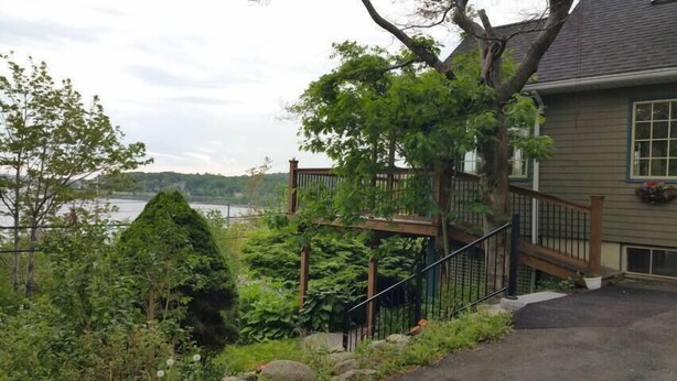 Une maison avec une terrasse en bois, un escalier et une vue sur un lac.