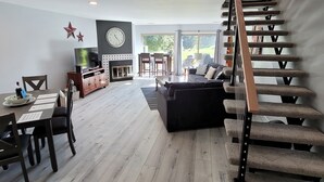 En rummelig opholdsstue med spisebord, sofa og trappe.