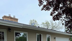 Einbungalow mit Veranda, Garage und einer Terrasse mit zwei Stühlen.