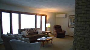 Ein Wohnzimmer mit einer Couch, Sesseln, einem Couchtisch, einer Lampe und einem Kamin.