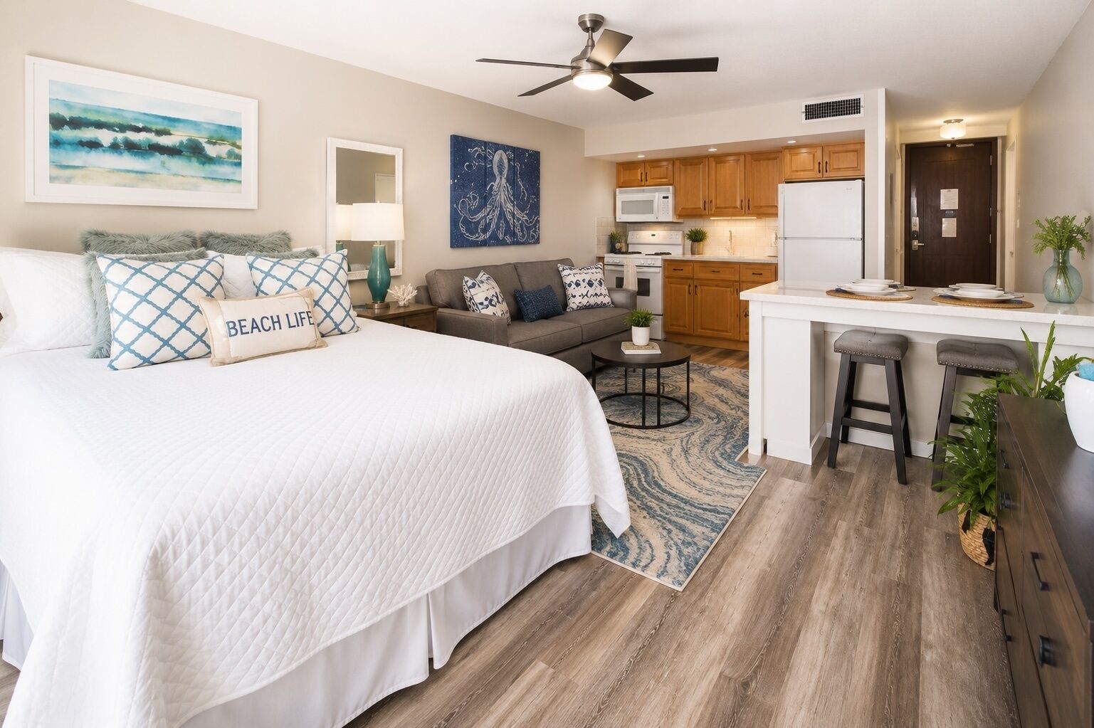 A compact living space with a bed, a sofa, a dining area, and a kitchenette.