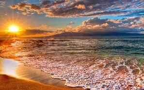 A beach with waves at sunset.