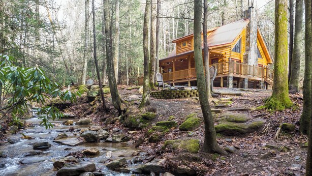 Eine Hütte, umgeben von einem Wald, durch den ein Bach fließt.