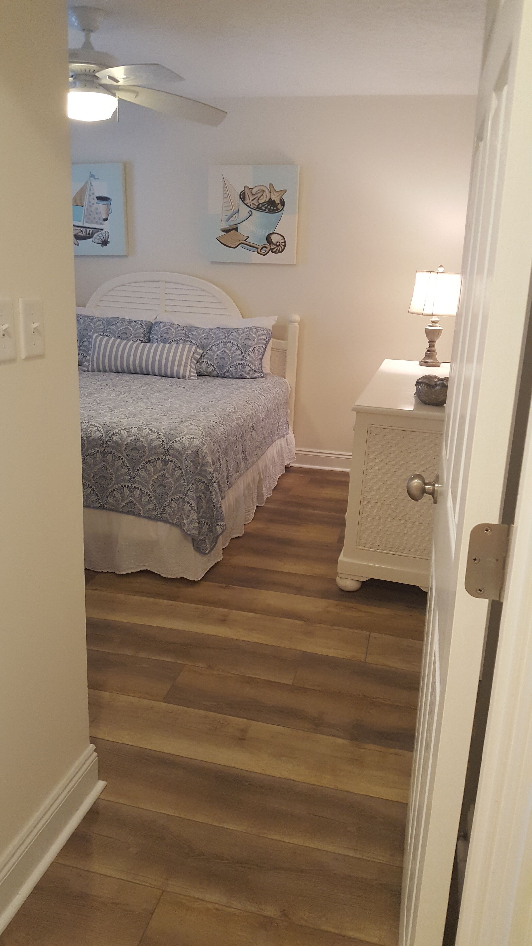 Ein Schlafzimmer mit Bett, Nachttisch, Lampe und Deckenventilator.