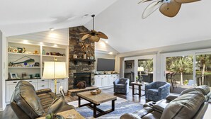 A spacious living area with a stone fireplace, leather sofas, and a television. - Waterfront View Perfect for Fun Loving Families!  (Hilton Head Island)