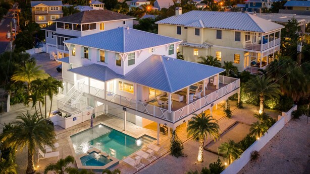 A large, multi-story house with a swimming pool, multiple balconies, and a covered patio area. - Dragonfly - Southern charm on the North end of Anna Maria Island (Anna Maria)