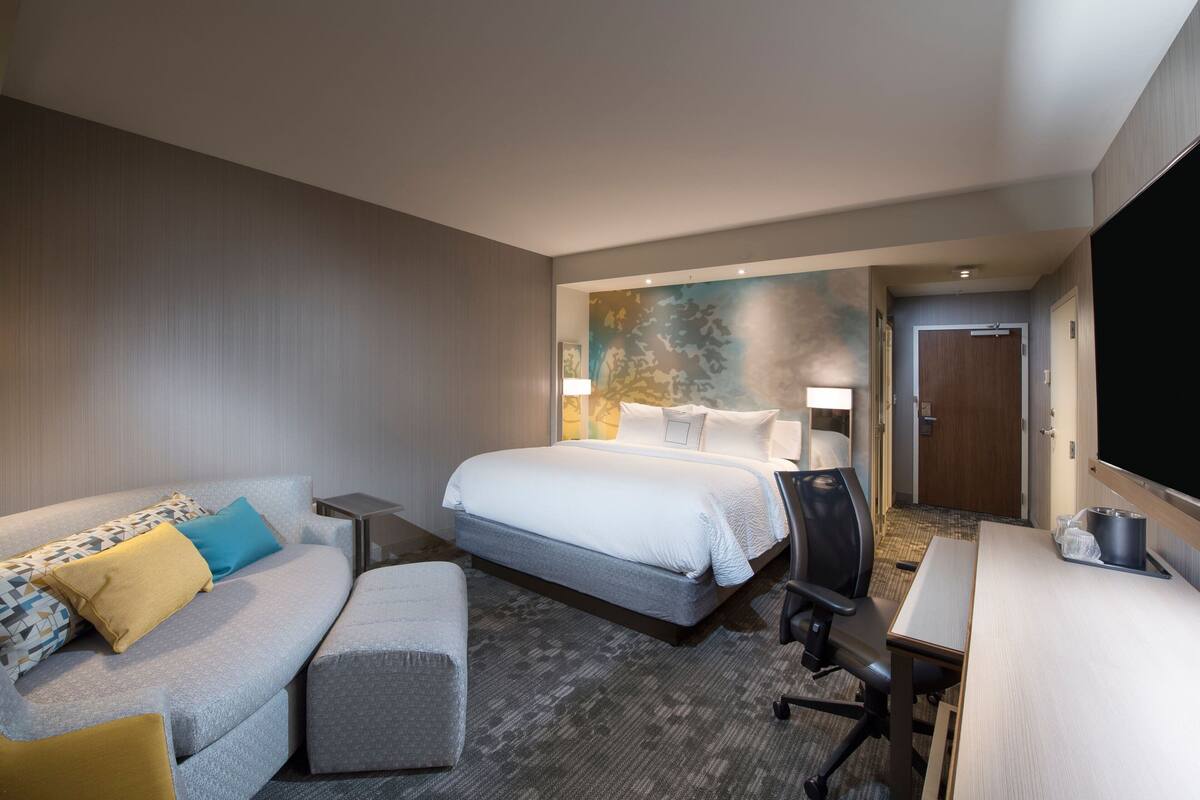 Una habitación de hotel con una cama, un sofá, un escritorio y un televisor.
