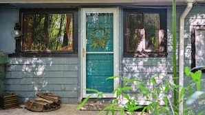 Una casa con puerta verde, ventana adornada con un adorno y farol en la pared.