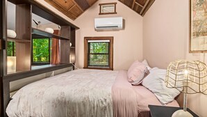 Un dormitorio con cama, ventana, equipo de aire acondicionado y ventilador de techo.