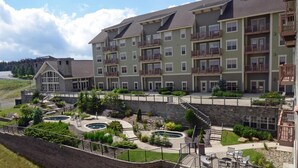 A multi-story residential building with balconies, a swimming pool, and a landscaped courtyard. - Soaring Eagle #406:  2 Bedrooms, 2 Full Baths:  Slope Side,  Hot Tubs. Underground Parking. (Snowshoe)