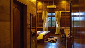 A wooden room with a bed, a table, and a window with curtains. - Heart of Wonder Villa (Siem Reap)