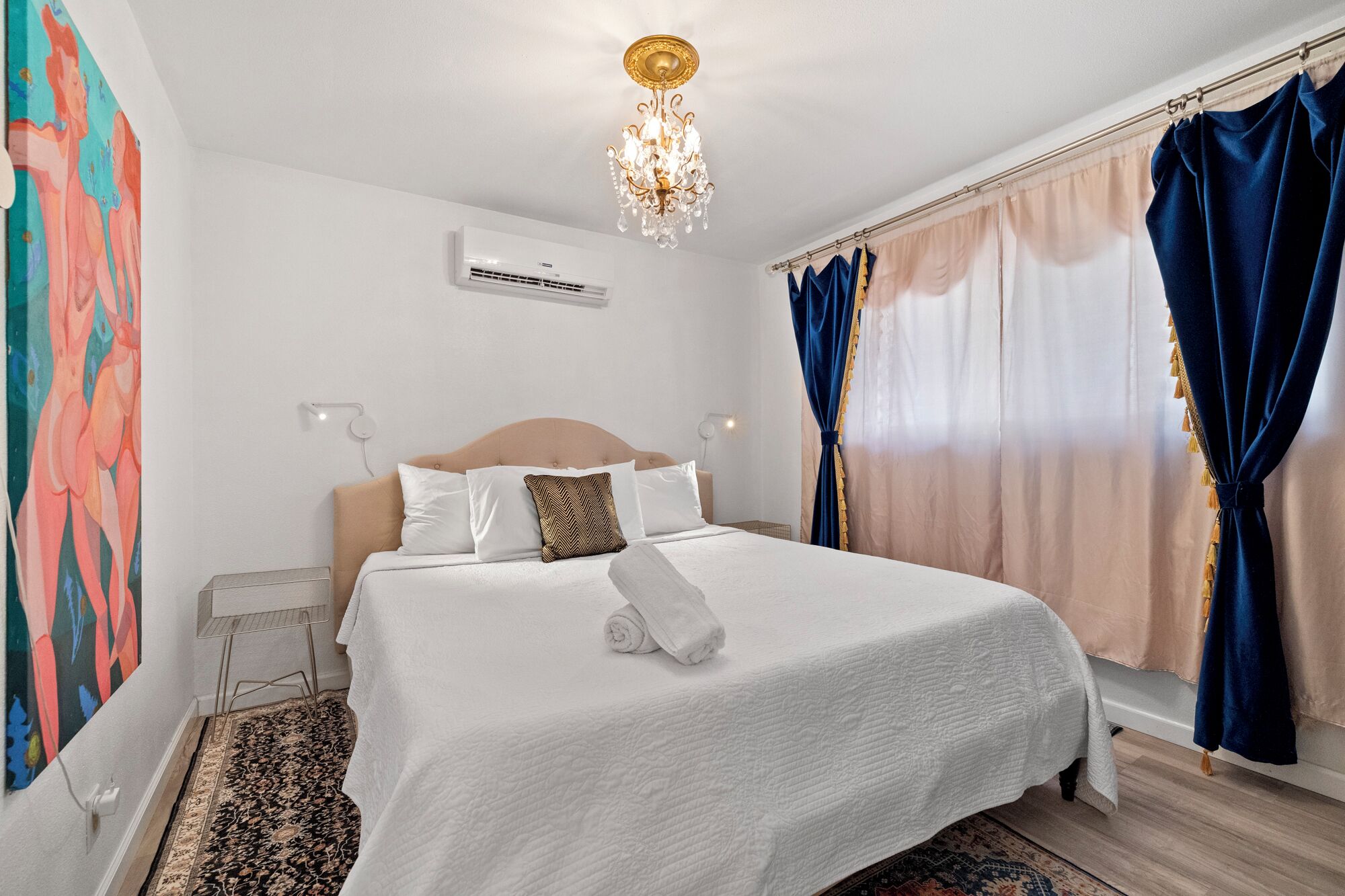 Une chambre d’hôtel avec un lit, un lustre, un appareil de climatisation et des rideaux.