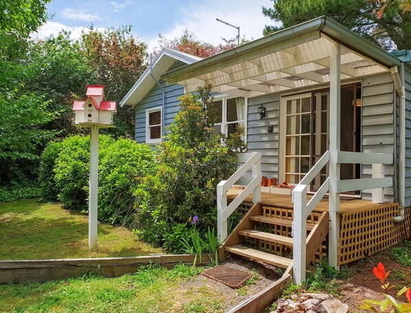A house with a porch, wooden steps, and a birdhouse.